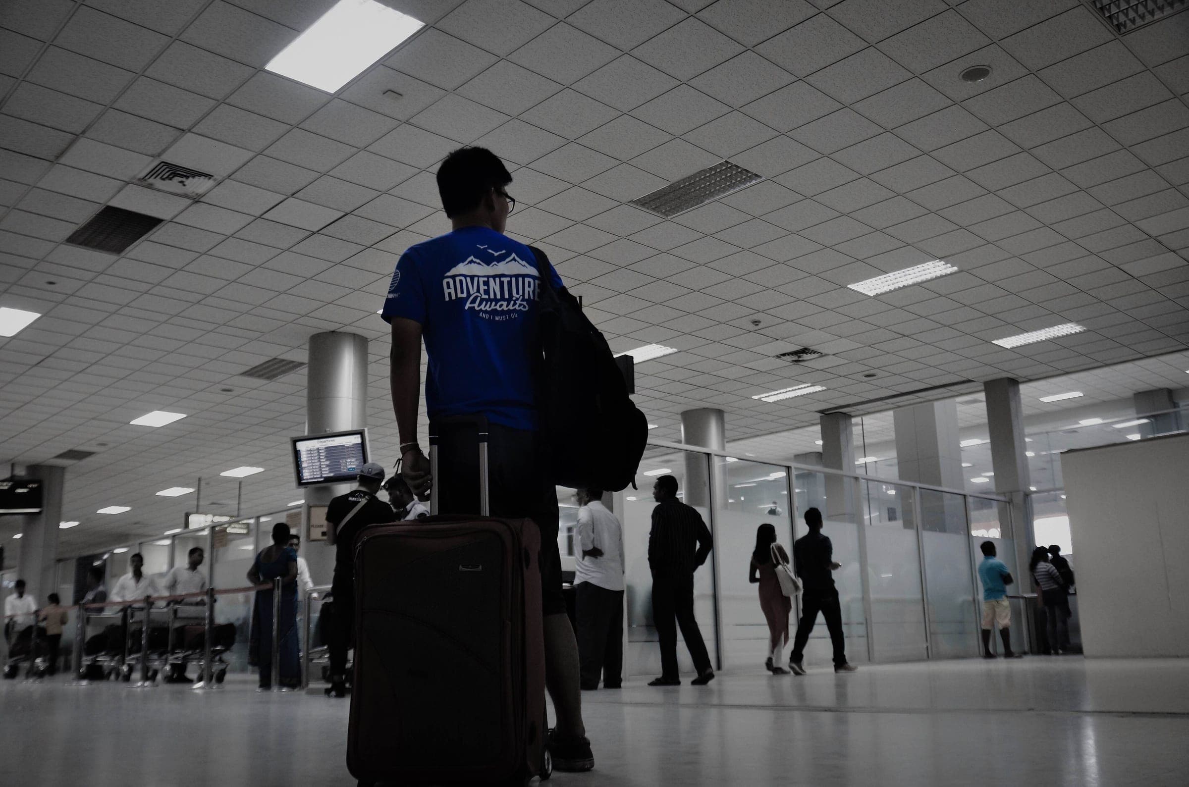 A young traveller with a suitcase walking through an airport hall